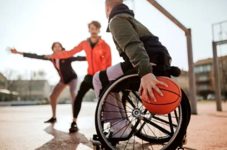 Individuals engaging in wheelchair basketball outdoors