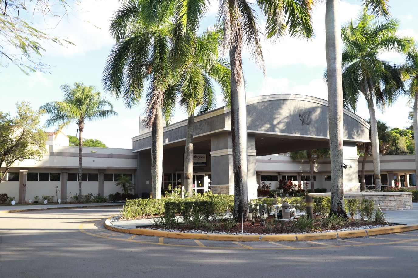 Exterior view of a senior living facility with palm trees