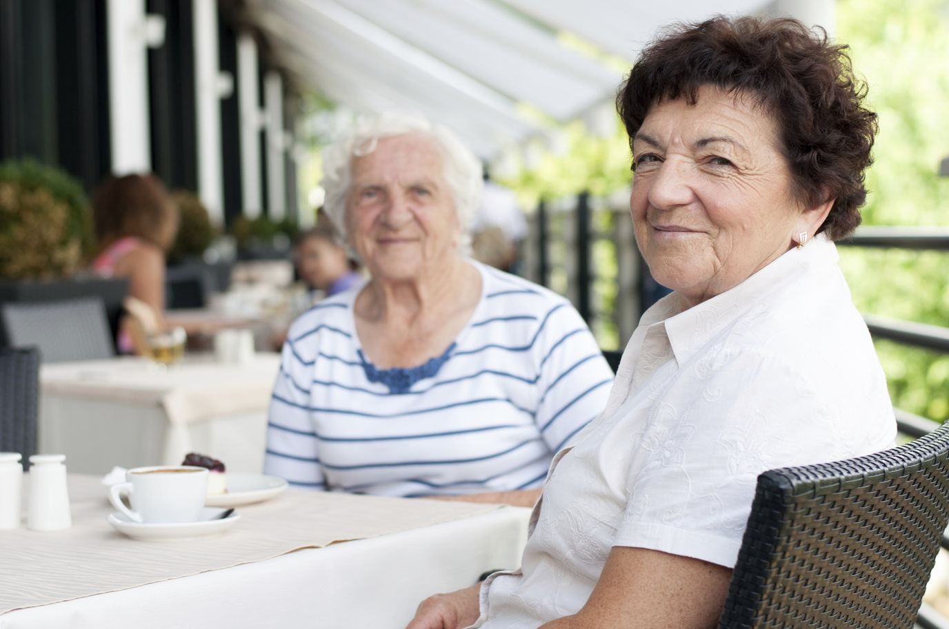 Two elderly women enjoying coffee outdoors