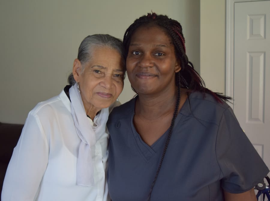 A resident and staff member smiling together indoors