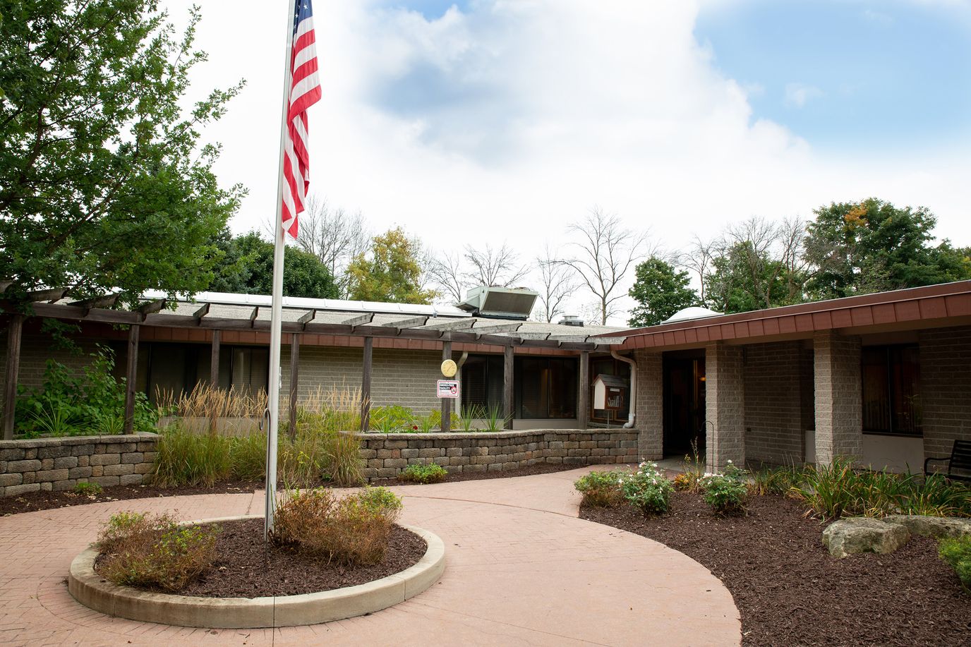 Exterior view of the facility entrance with landscaping and flag