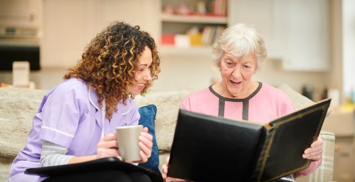 A caregiver and resident looking at a photo album together.