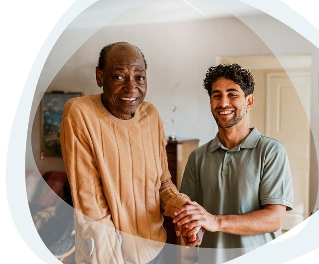 A caregiver and resident smiling in a warm interior space