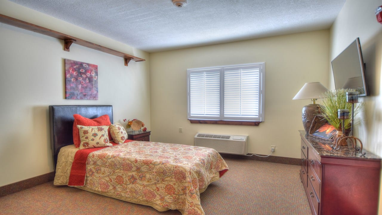BeeHive Homes of Bernalillo, assisted living in Bernalillo, NM — Cozy bedroom with a floral-patterned bedspread and television
