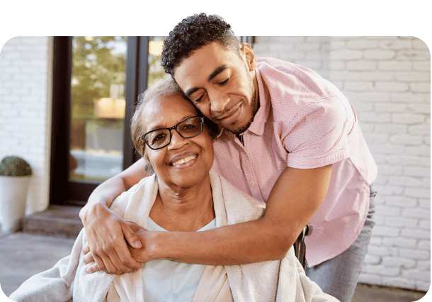 A caregiver hugging a smiling resident outdoors