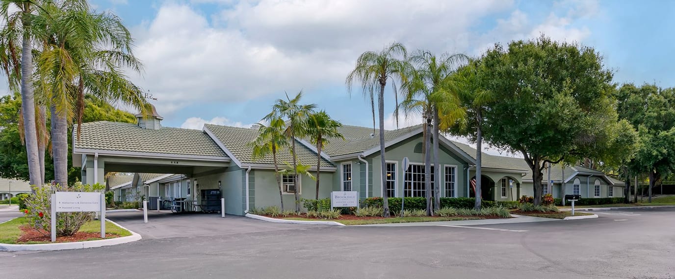 Exterior view of a senior living facility with palm trees