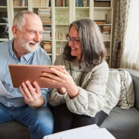 Two residents engaging with a tablet in a cozy living space