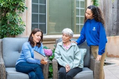 Caregiver discussing with residents in a garden setting