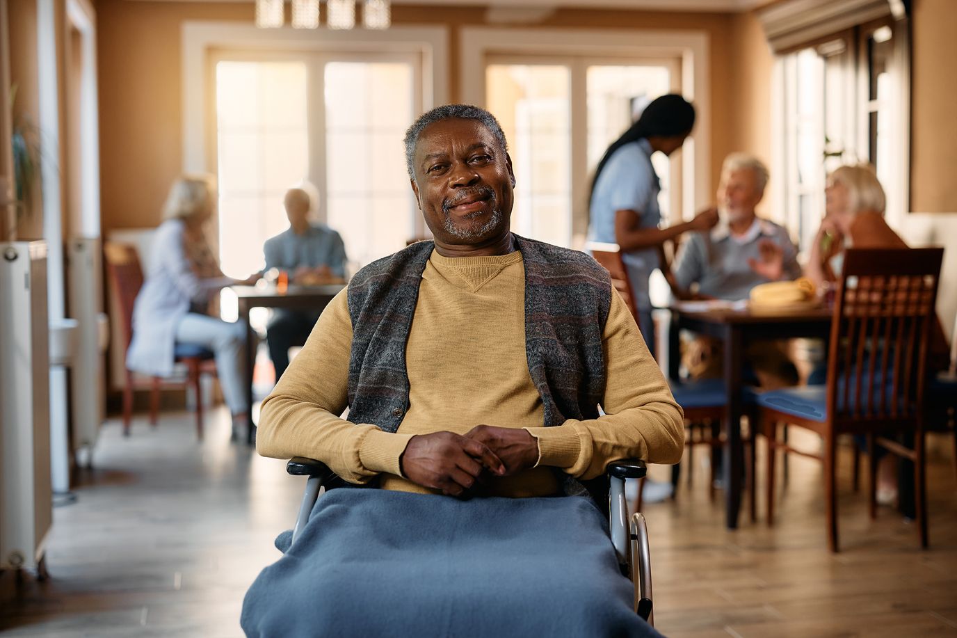 A resident enjoying time in a common area with staff and visitors