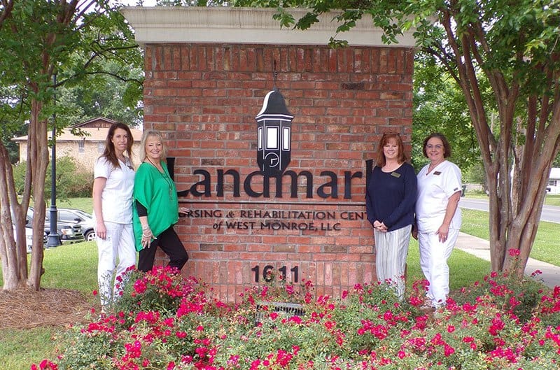 Staff members pose in front of facility sign