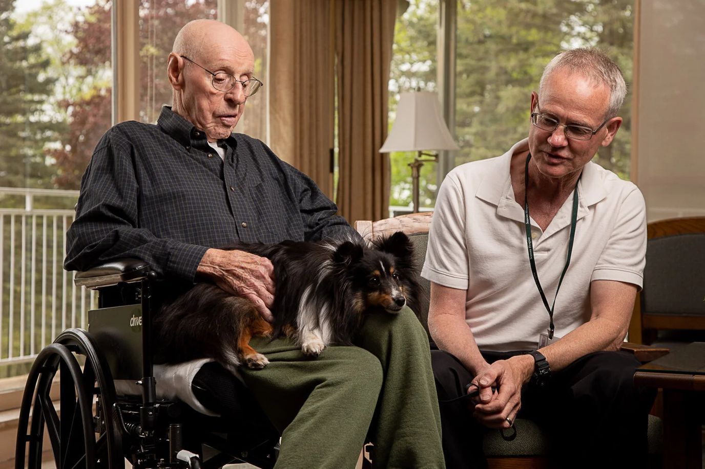 An elder resident with a dog and a staff member