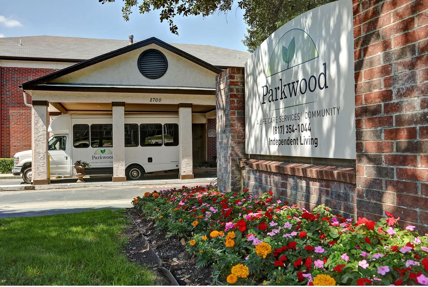 Exterior view of Parkwood facility with a shuttle and flowers.