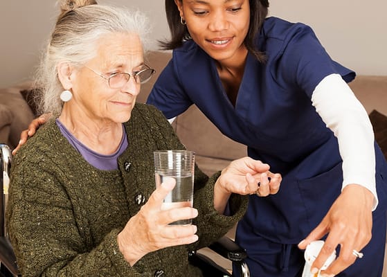 Caregiver assisting an elderly woman with a drink