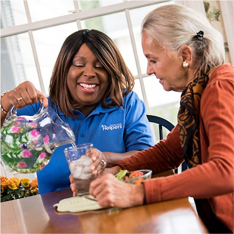 Staff member assists a resident with a drink.
