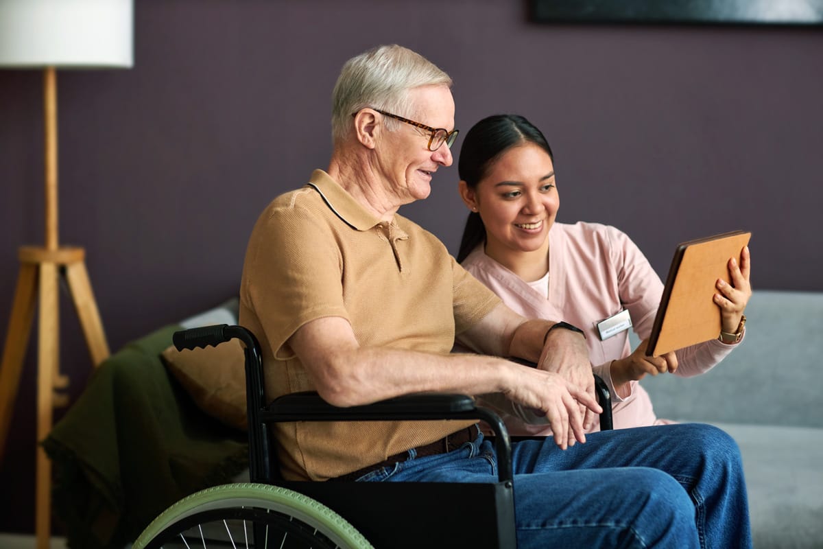 A smiling resident and staff member engaging with a tablet.
