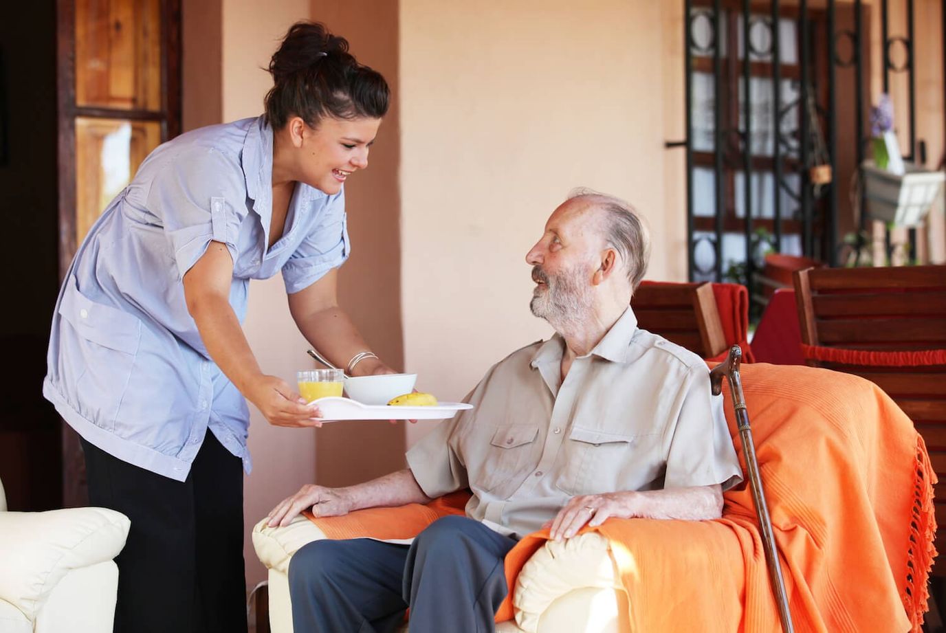 Bluebird Homecare – Charlotte, home care in Charlotte, NC — Caregiver serving food to a senior man in a lounge
