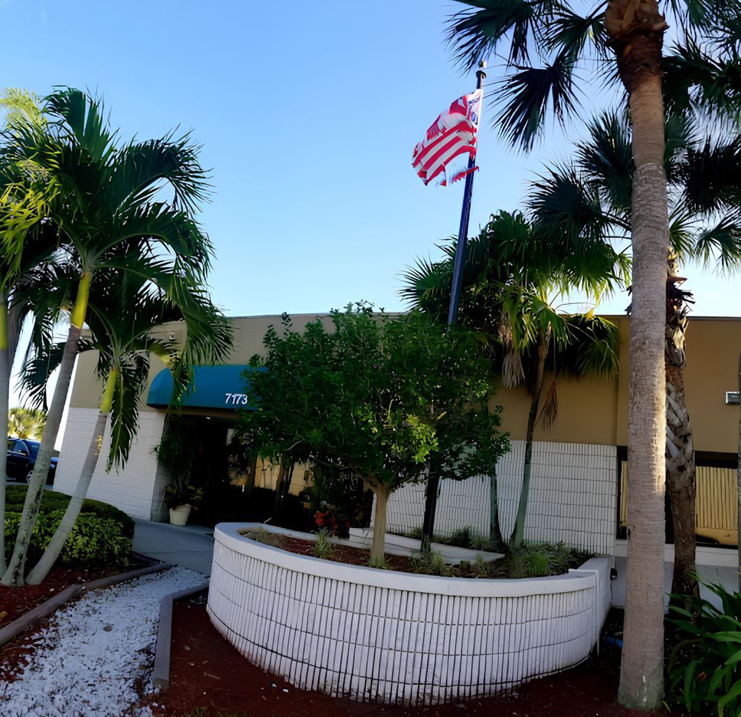 Exterior view of nursing facility with flag and palm trees