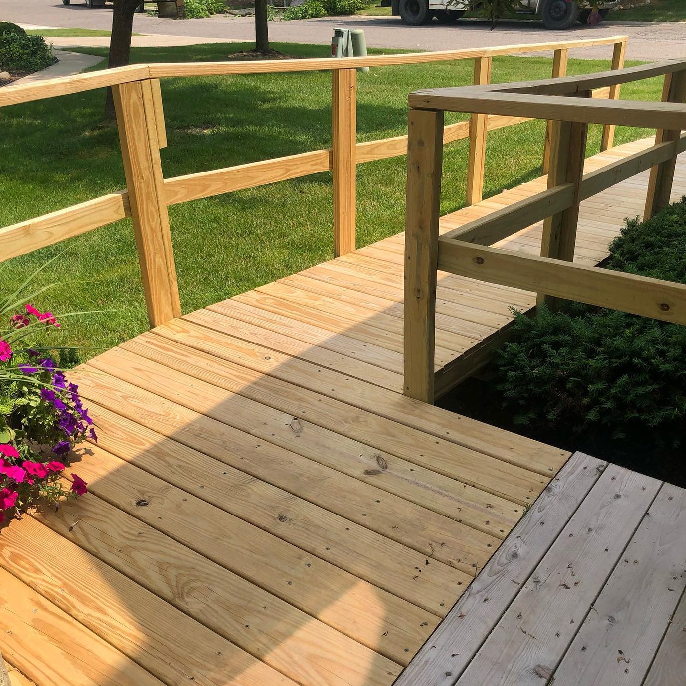 A wooden ramp leading to a grassy area with flowers