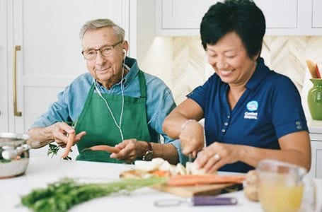 Residents and staff cooking together in a bright kitchen