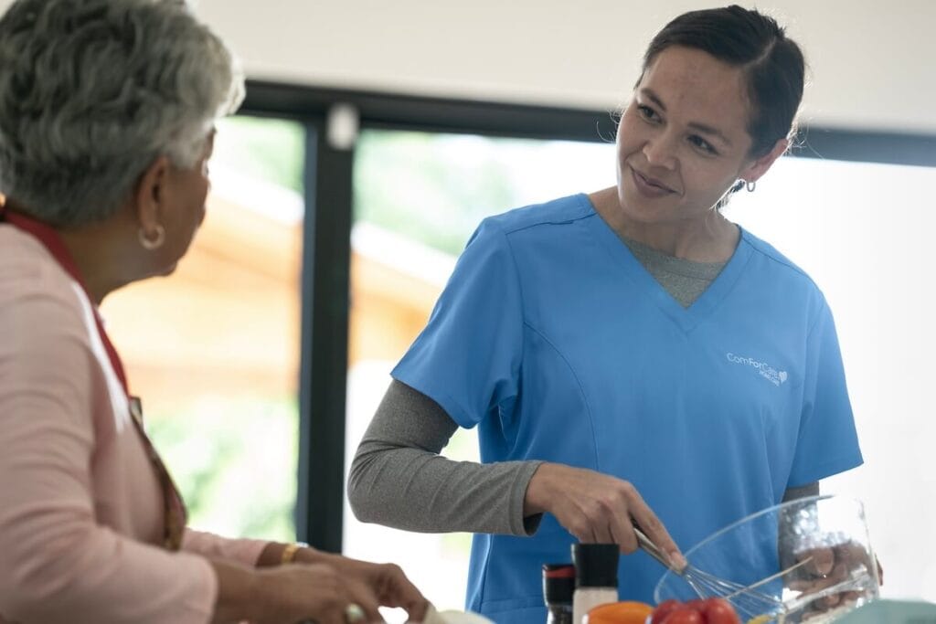 Staff member engaging with resident while preparing food.