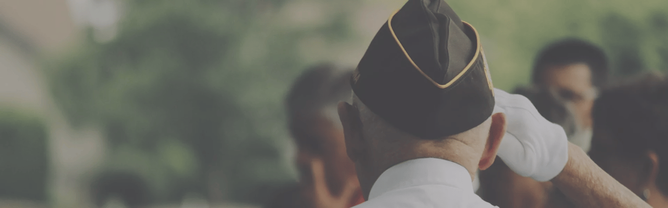 Elderly person in military hat saluting