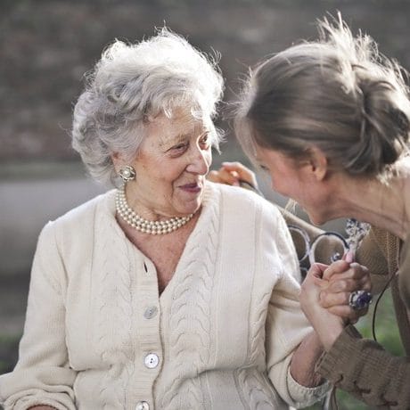 Resident and caregiver enjoying conversation outdoors.