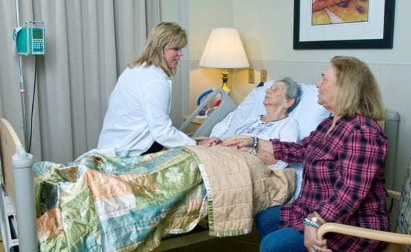 A nurse interacting with two residents in a care room