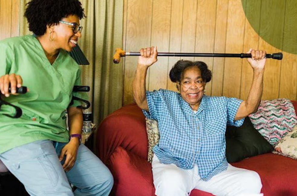 Resident exercising with a staff member in a cozy interior