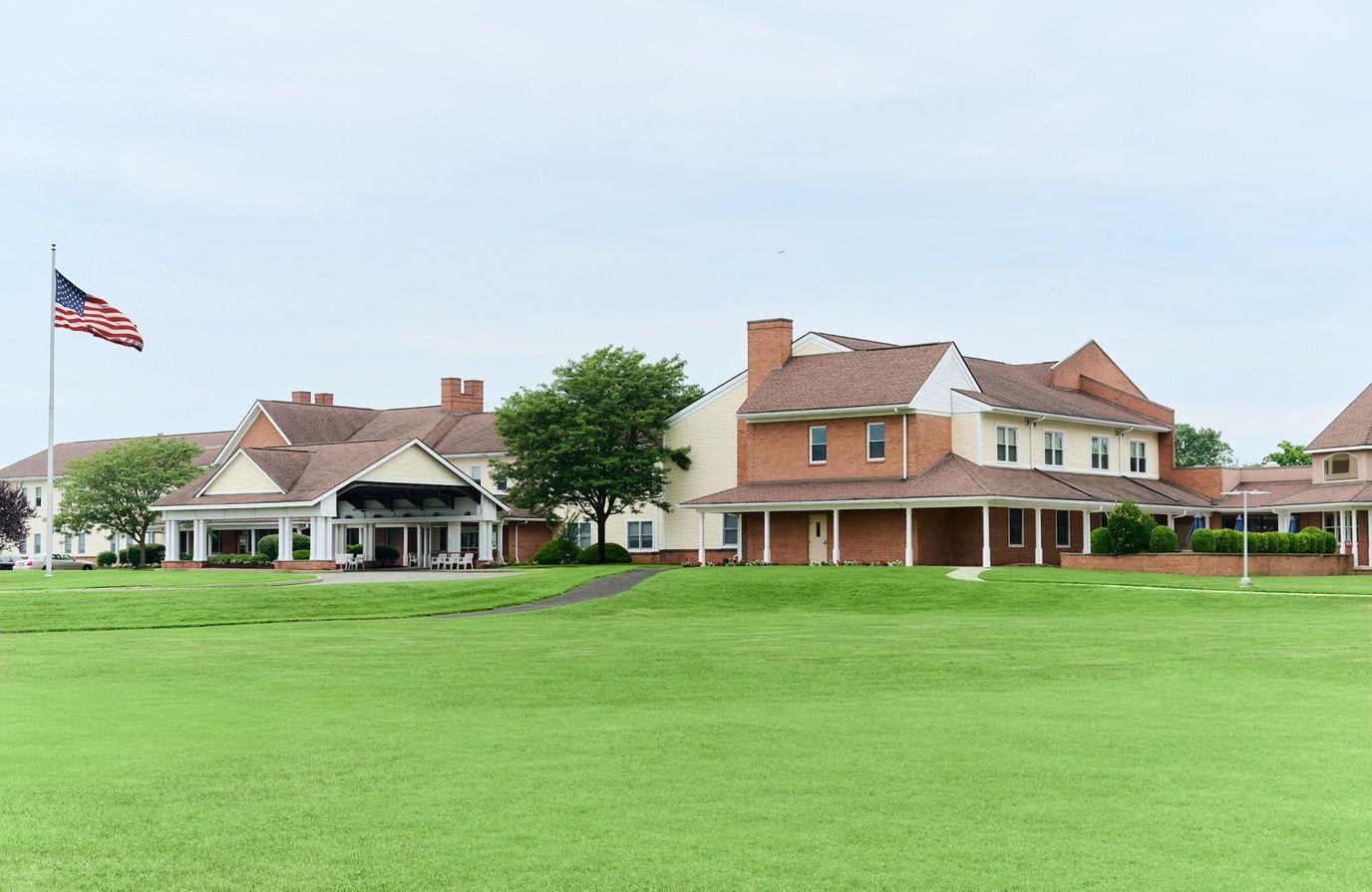 Exterior view of a nursing home with flag and lawn