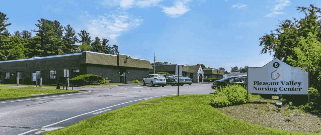 Exterior view of Pleasant Valley Nursing Center with vehicles parked