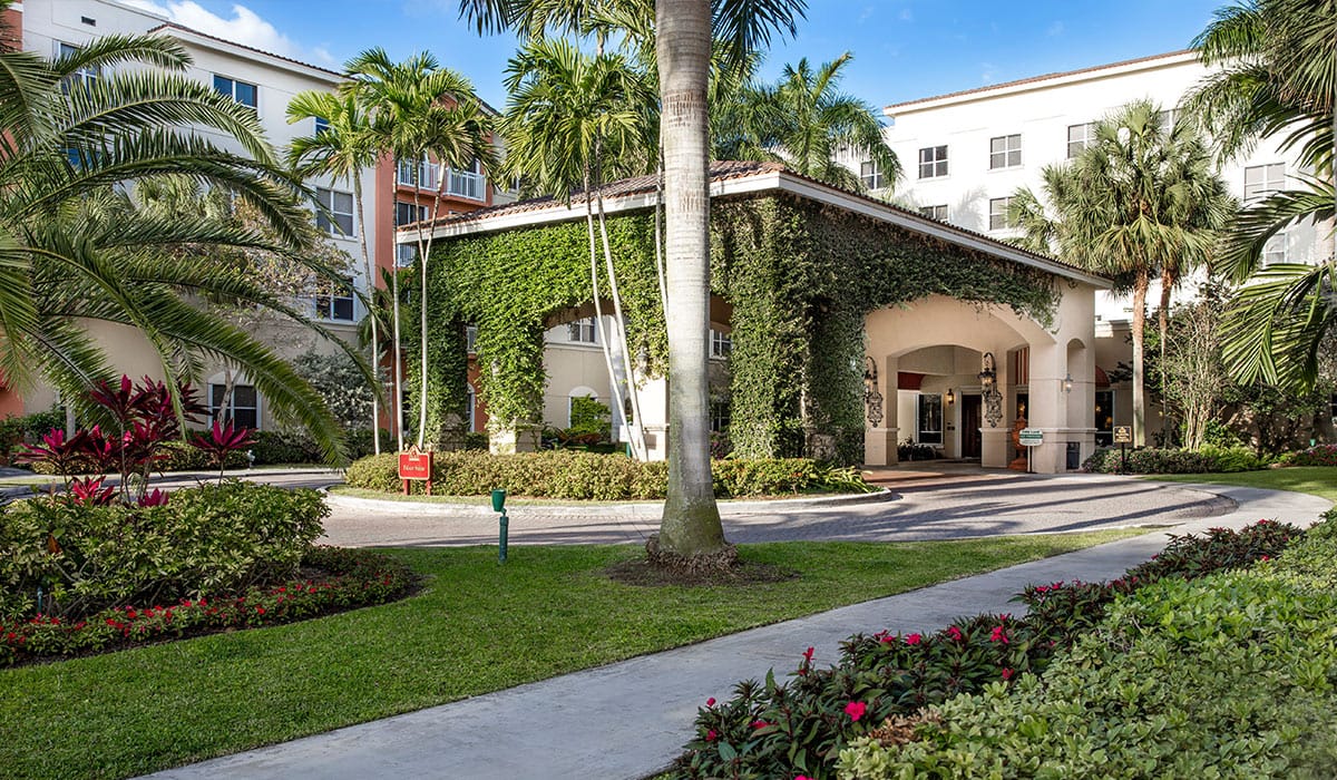 Exterior view of The Palace Suites entrance surrounded by greenery