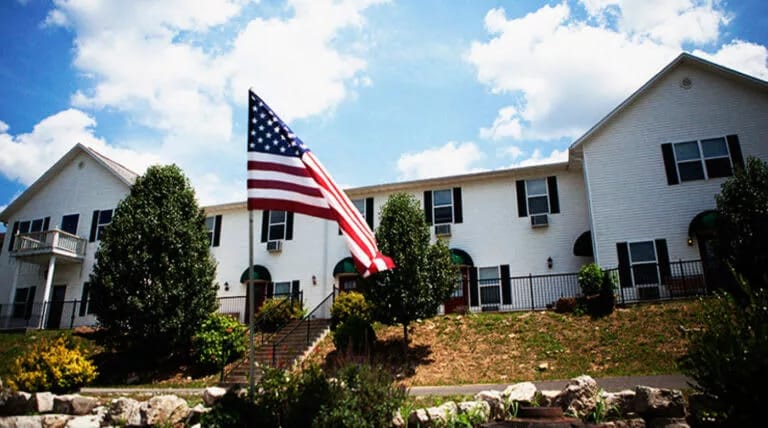 Exterior view of a senior living facility with an American flag