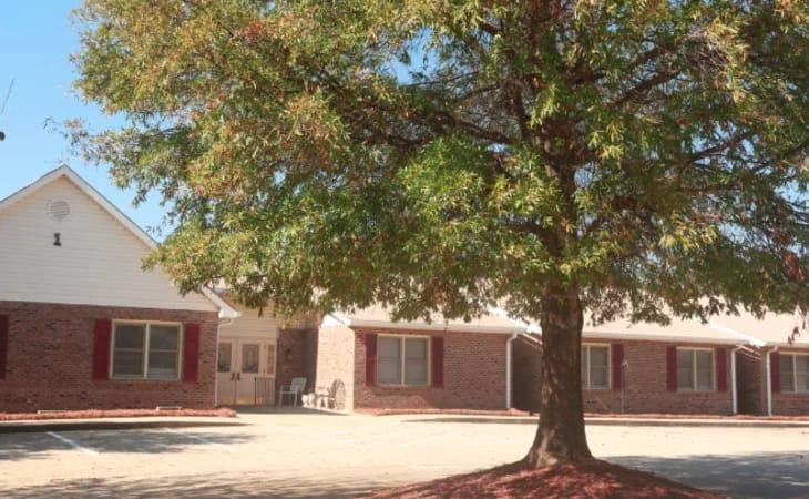 Exterior view of the facility with a large tree