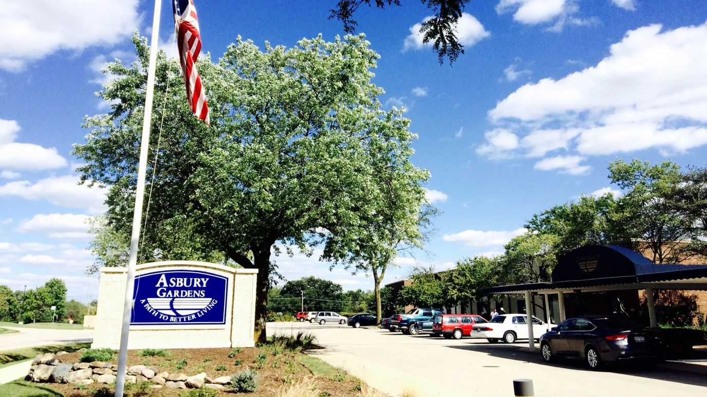 Exterior view of Asbury Gardens with sign and trees