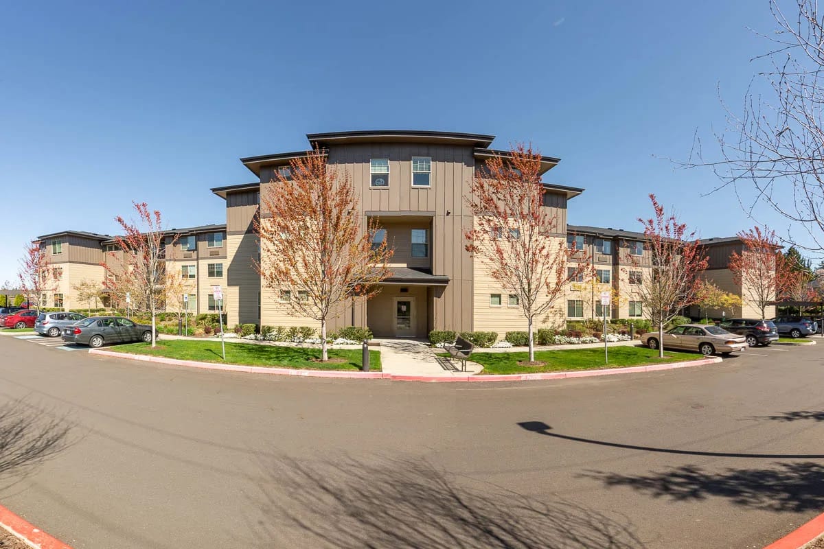 Exterior view of the senior living facility with trees and parking