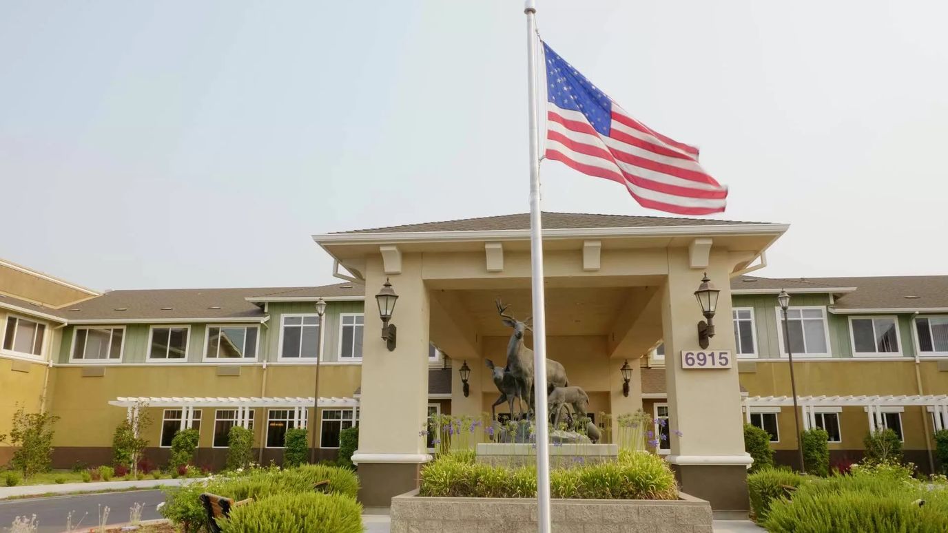 Front entrance of Carlton Senior Living Elk Grove with flag