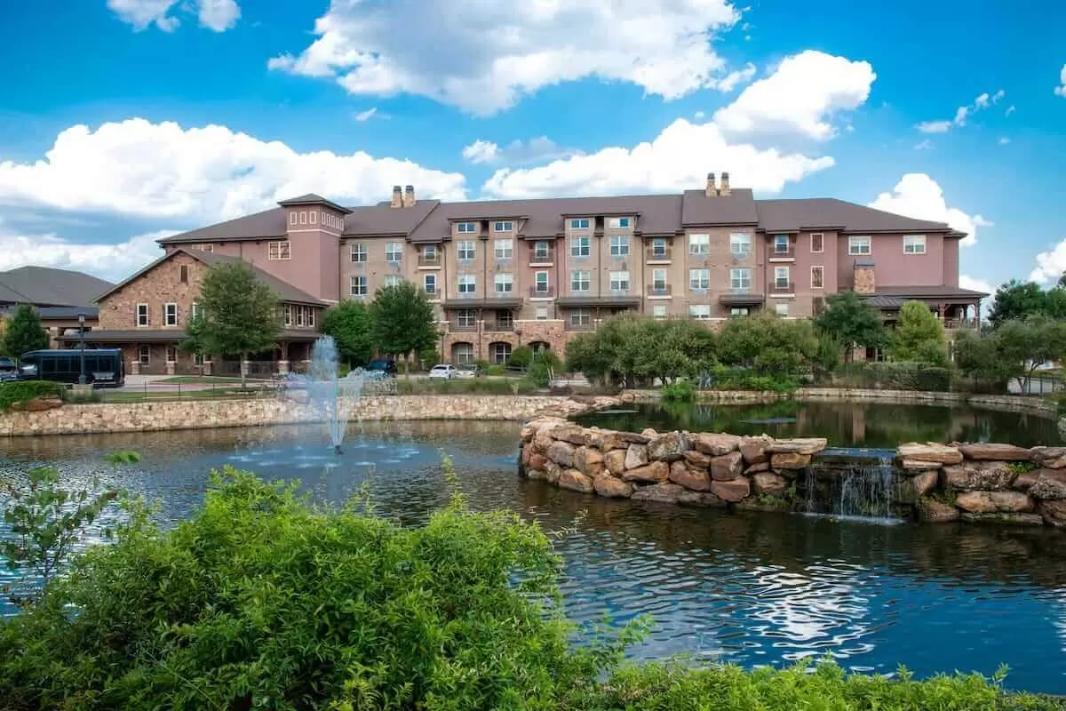 Exterior view of a senior living facility by a pond