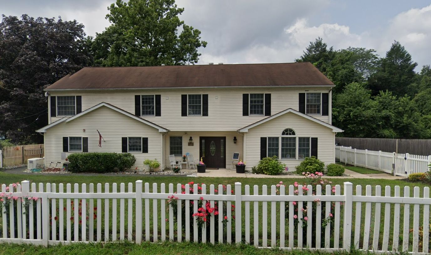 Exterior view of a senior living facility with a white fence