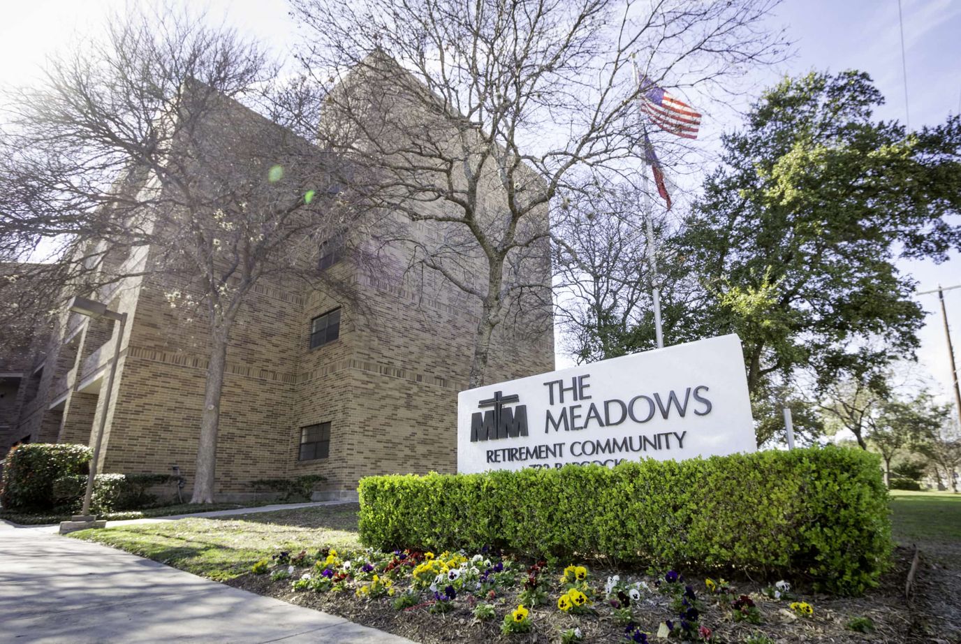 Exterior view of The Meadows Retirement Community with signage and flowers