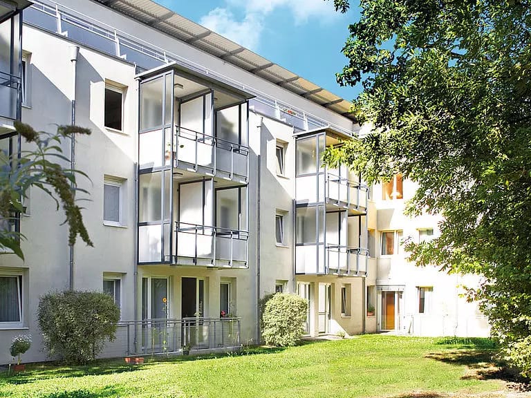 Exterior view of a senior living building with gardens