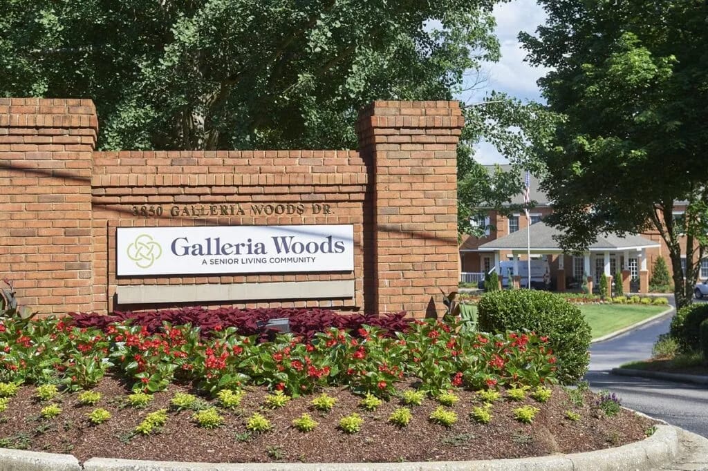 Entrance sign of Galleria Woods with flowers