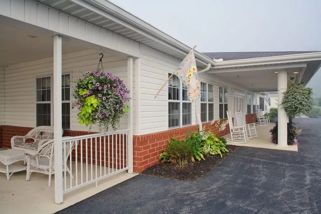 Exterior view of a senior living facility with a porch and hanging plants