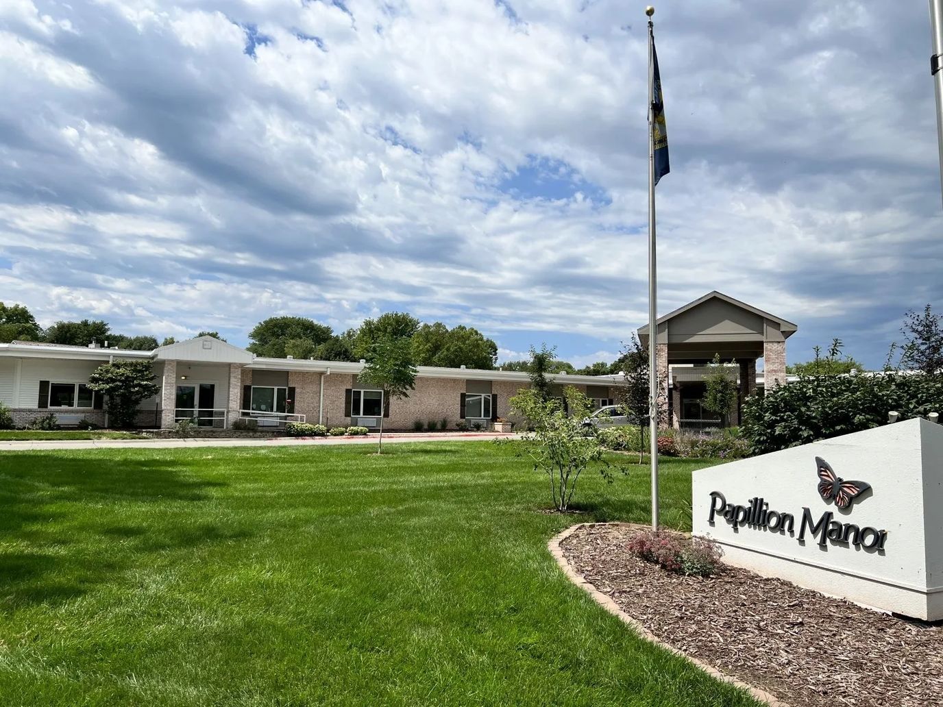 Front exterior of Papillion Manor with landscaped lawn