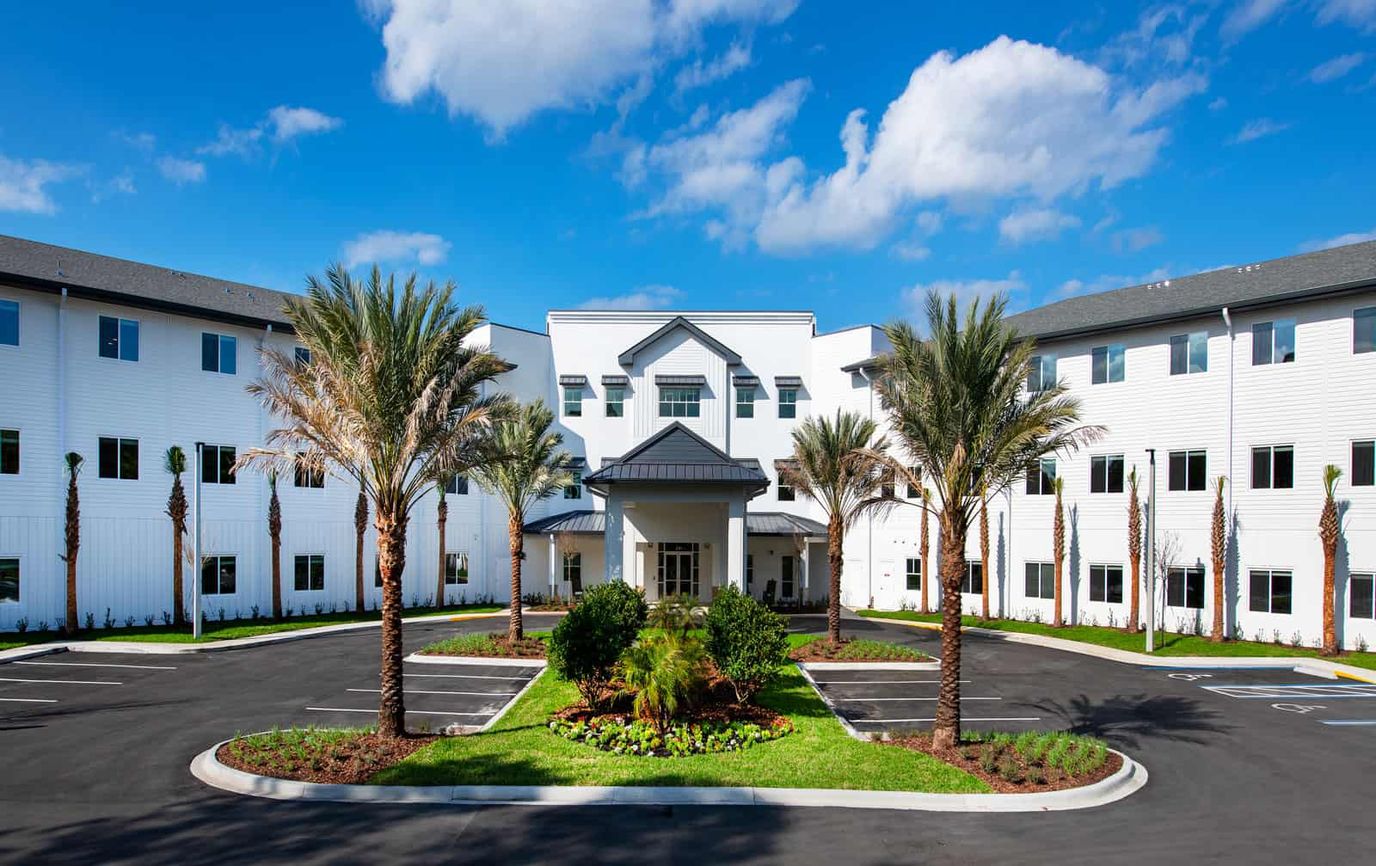 Exterior view of an assisted living facility with palm trees
