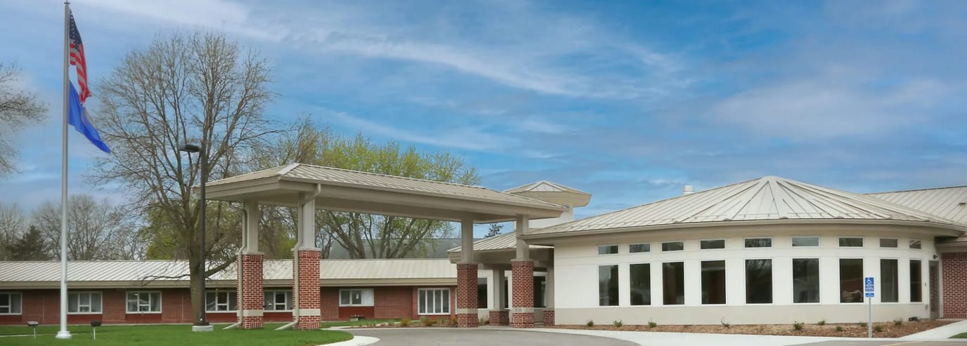 Exterior view of Pine Haven Nursing Home with flag and trees