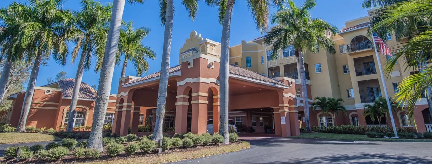 Exterior view of a senior living facility surrounded by palm trees