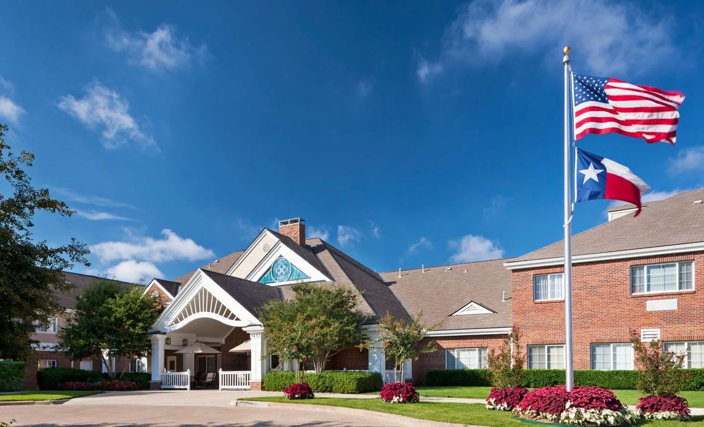 The exterior of The Monarch at Richardson with flags and landscaping