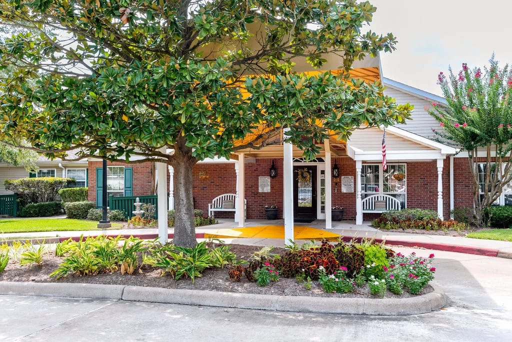 Entrance of a senior living facility with gardens and seating