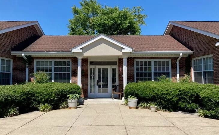 Front entrance of a senior living facility surrounded by greenery