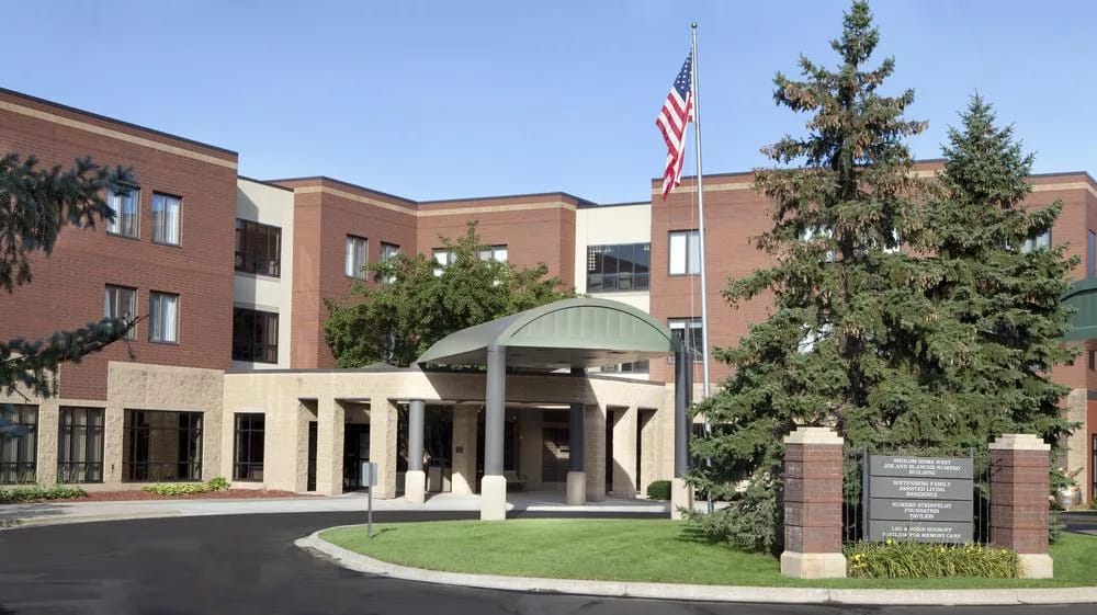 Front exterior view of a senior living facility with flag